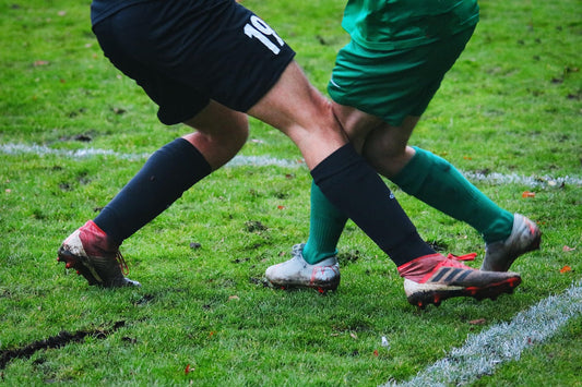 Two men collide at the knee playing a game of soccer