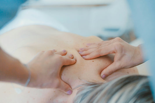 Two hands press a shoulder blade on a bare back