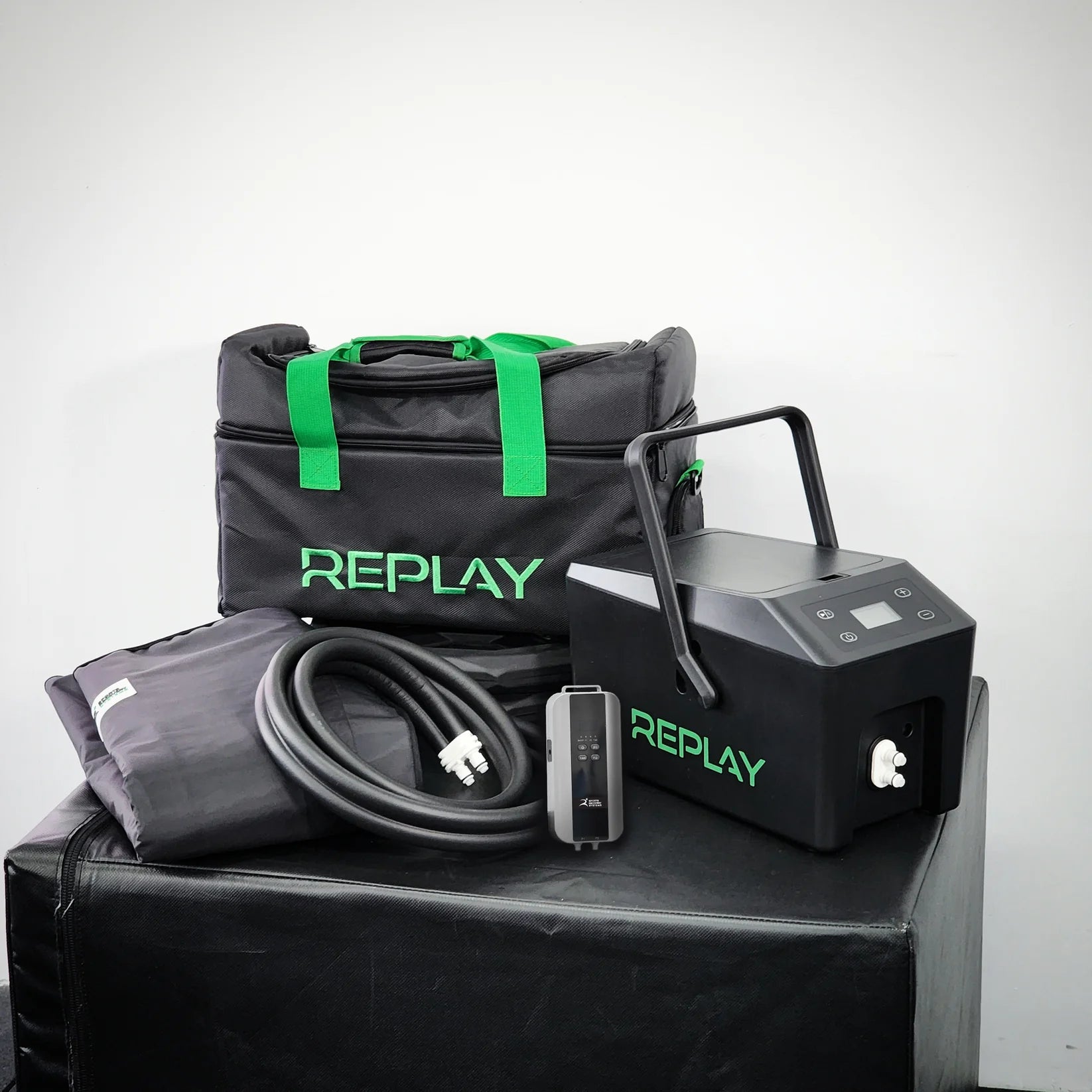 Black knee replacement recovery equipment sits on a black table with the word Replay in green on bag and control box